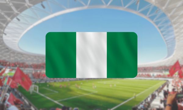 A blurred stadium background with the Nigerian flag highlighted in the foreground.